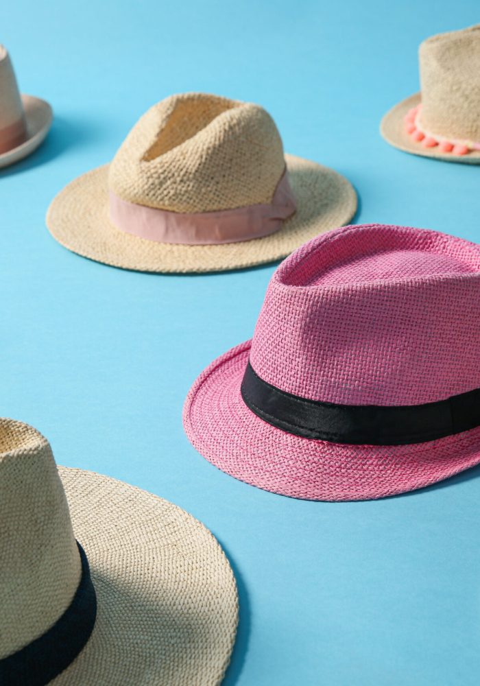 One pink hat among others on turquoise background. Diversity concept